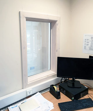 Installation of wooden window to improve light and vision within a school reception area.